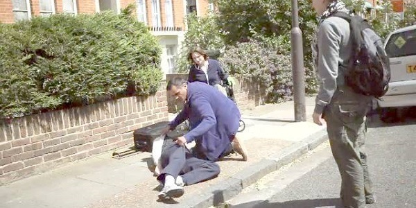 A person helps someone unconscious on a sidewalk. 