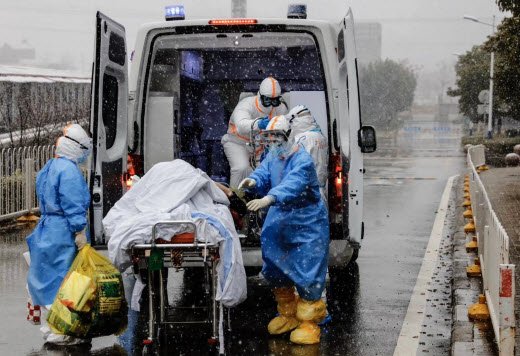 medical staff loading patient into ambulance wearing PPE