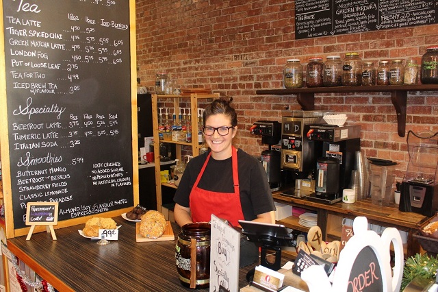 Femme derrière le comptoir d'un café, souriante