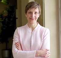 Woman with short hair, smiling in a pink suit