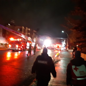 A paramedic and a Red Cross volunteer walk towards an emergency in the evening