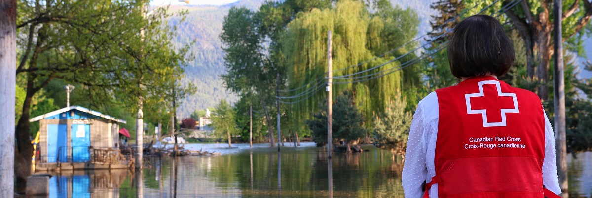 Un bénévole de la Croix-Rouge canadienne regarde une rue inondée