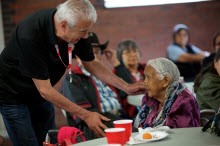 Man talking to older woman with his hand on her shoulder