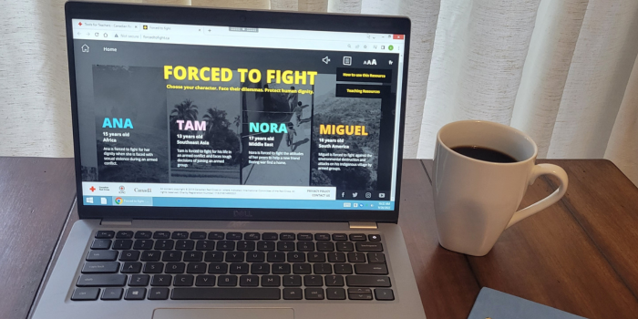 ForcedtoFight.ca sur un ordinateur portable, tasse de café et un bloc-notes sont posés sur la table.